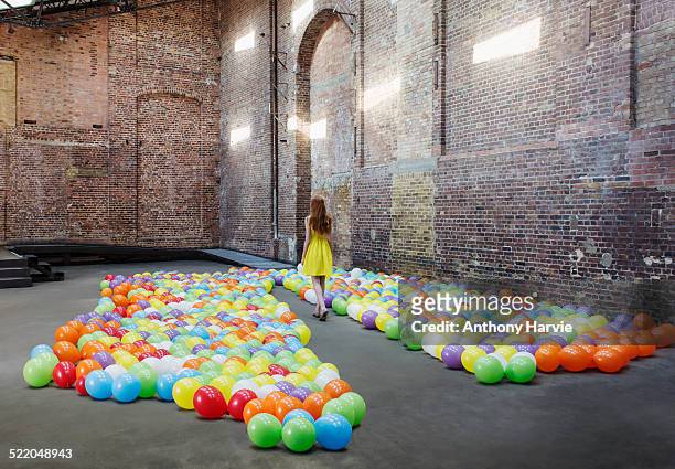 woman in warehouse with colourful balloons - installationskunst stock-fotos und bilder