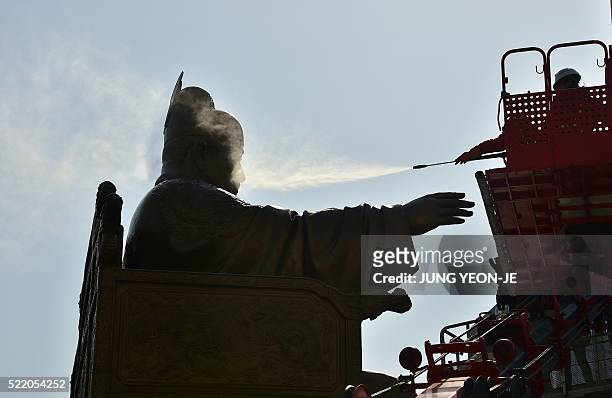 South Korean worker uses water to wash a bronze statue of King Sejong, the 15th century Korean king, during a street and park clean-up event for...