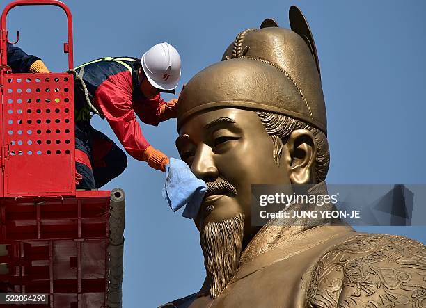 South Korean worker wipes a bronze statue of King Sejong, the 15th century Korean king, during a street and park clean-up event for springtime at...