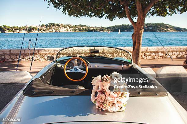 wedding bouquet and classic convertible car parked on coast of villefranche-sur-mer, france - ranunculus wedding bouquet stock pictures, royalty-free photos & images