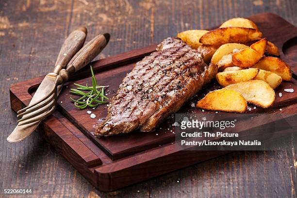 well done grilled new york steak with roasted potato wedges on c - lob wedge stock-fotos und bilder