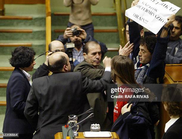 Partido Popular representative in the Basque Parliament board Carmelo Barrio tries to catch one of the posters shown by unidentified people who...