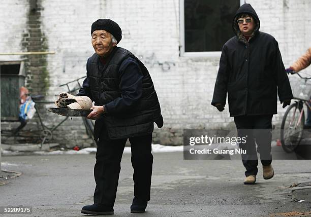 An elderly woman carries the ashes of heating coal on February 17, 2005 in Beijing, China. China, the world's second biggest greenhouse gas emitter...