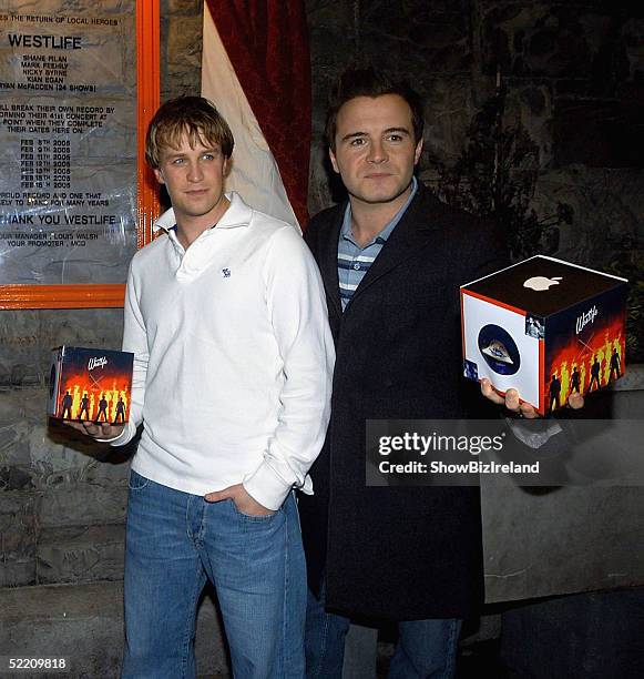 Kian Egan and Shane Filan of Westlife hold up their special Westlife branded i-pod after being presented with a special plaque as they will have...