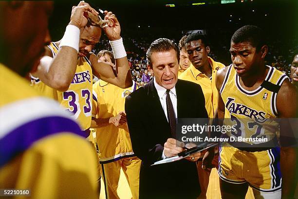 Head Coach Pat Riley of the Los Angeles Lakers draws up a play during a timeout for Magic Johnson and Kareem Abdul Jabbar during an NBA game circa...