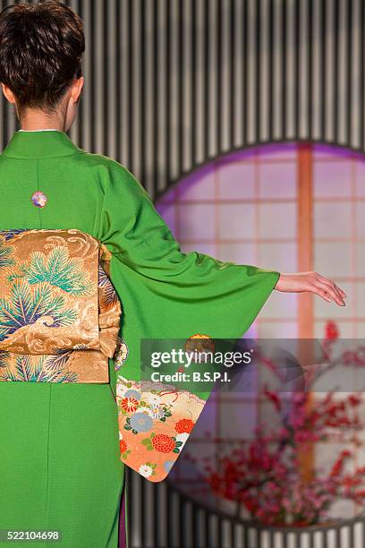 a detailed view shows a young japanese woman modeling a traditional kimono with silk obi sash at the nishijin textile center, located in the old downtown nishijin weaving district of kyoto, japan. - obi sash fotografías e imágenes de stock