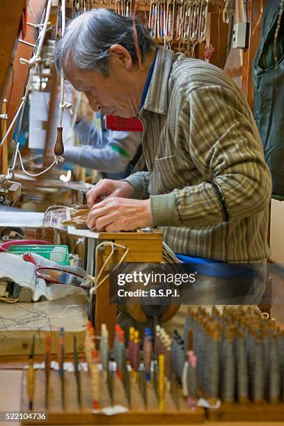 a detailed interior view shows an artisan weaving a silk kimono obi sash on a wooden loom at the kawamura orimono silk weaving workshop (an imperial-family designated weaver), located in the old downtown nishijin weaving district of kyoto, japan. - obi sash fotografías e imágenes de stock