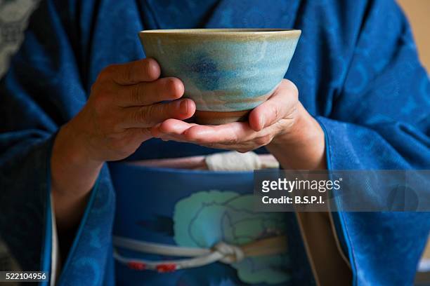 an interior view shows a woman in traditional kimono holding a teabowl during a tea ceremony in the tearoom of a residence near shugakuin in the sakyo district of northeast kyoto, japan - traditional culture stock-fotos und bilder