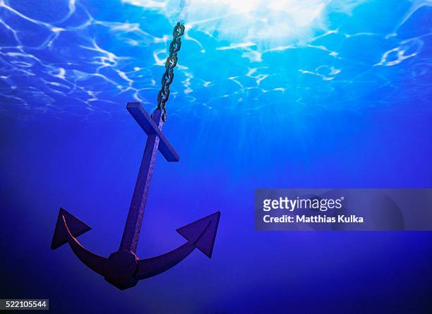 anchor in clear blue sea - anchor chain stock pictures, royalty-free photos & images