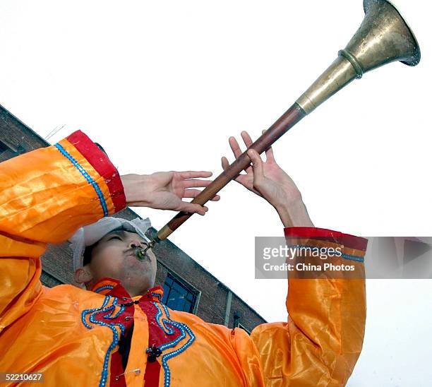 An actor plays a Chinese trumpet while performing the Niuyangge Dance at a government office, to welcome people coming back to work from holiday on...