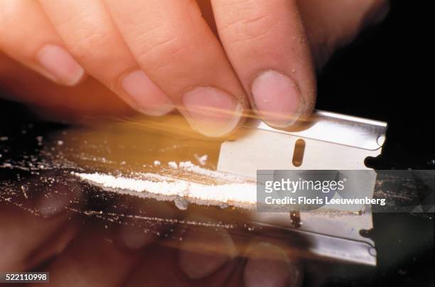 cutting line of cocaine with razor blade - cocaine stock pictures, royalty-free photos & images