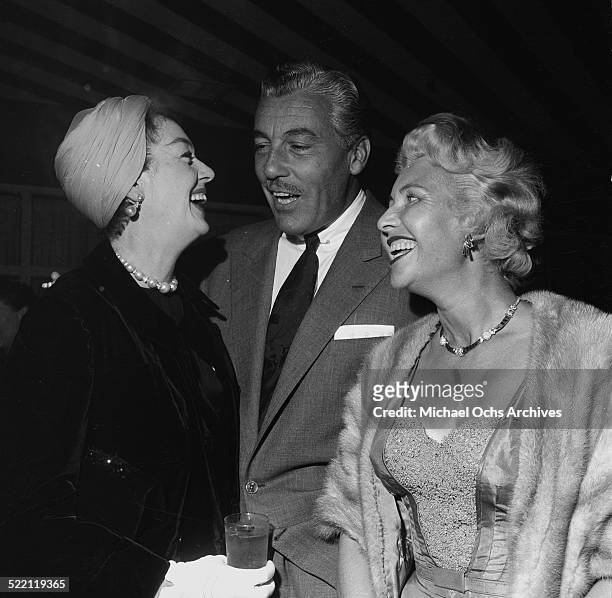 Actress Rosalind Russell talks with actor Cesar Romero during a party in Los Angeles,CA.