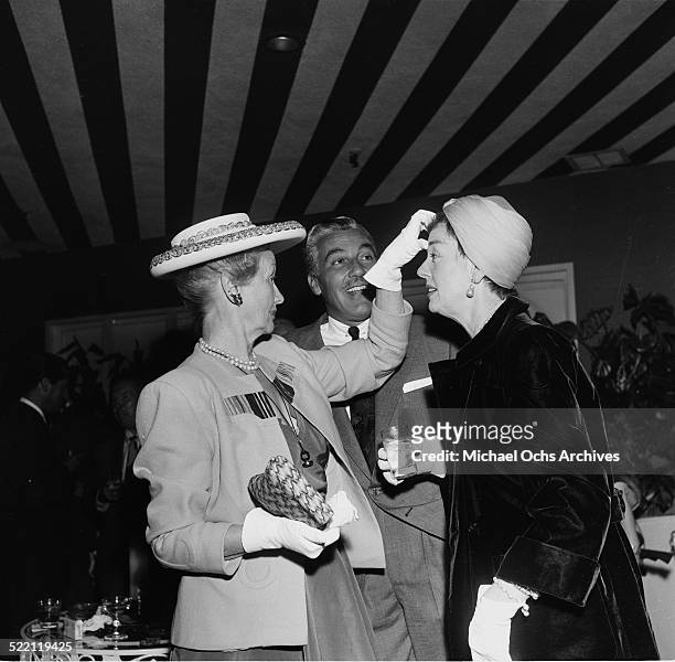 Actress Rosalind Russell talks with gossip columnists, Hedda Hopper and actor Cesar Romero during a party in Los Angeles,CA.