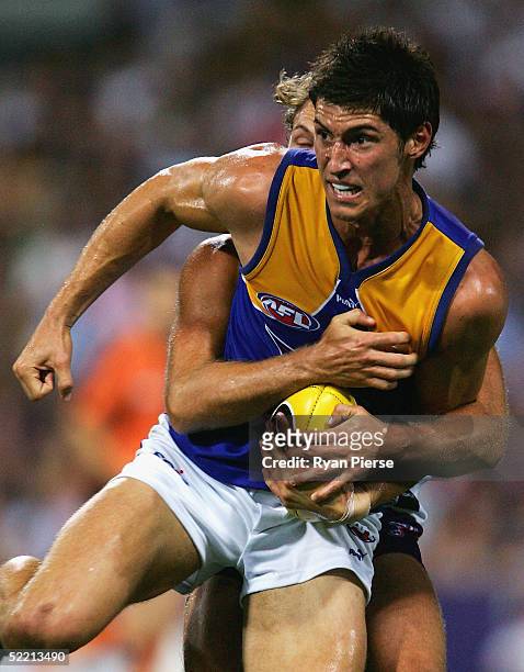 Tyson Stenglein for the Eagles is tackled by James Walker for the Dockers during the round one AFL Wizard Cup match between the Fremantle Dockers and...