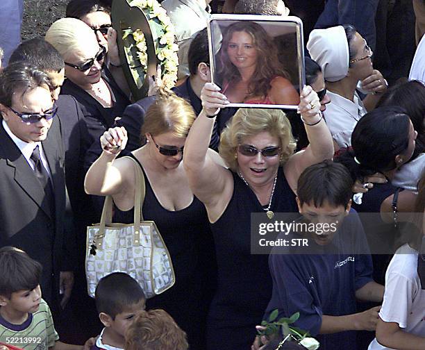 Cecilia Cubas aunt holds a portrait of her niece during Cecilia's burial at the Italian cemetery in Asuncion, 18 February 2005. Five months after she...