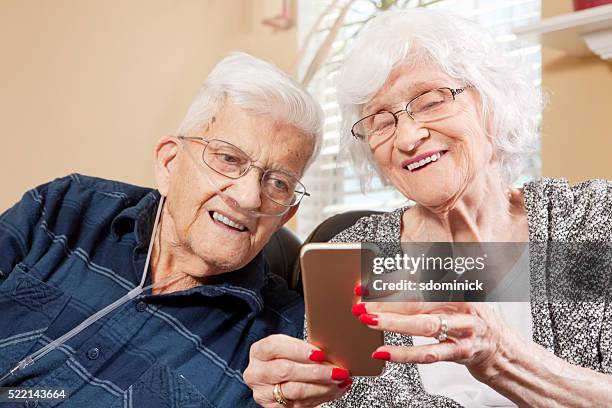 senior pareja mirando teléfono inteligente - medical oxygen equipment fotografías e imágenes de stock