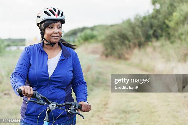 african american woman riding bike in park - adult riding bike through park stock pictures, royalty-free photos & images