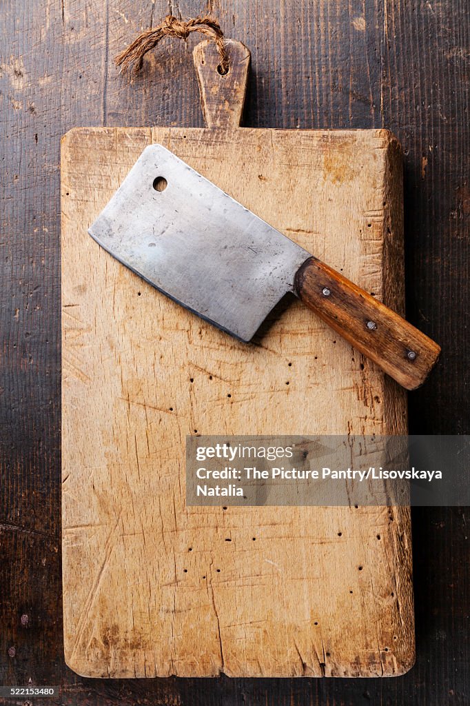 Chopping board and Meat cleaver on dark wooden background