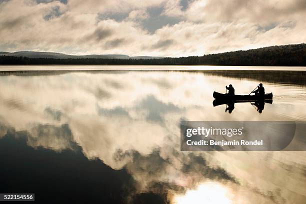 two people canoeing on lake - two people canoeing on a lake stock pictures, royalty-free photos & images