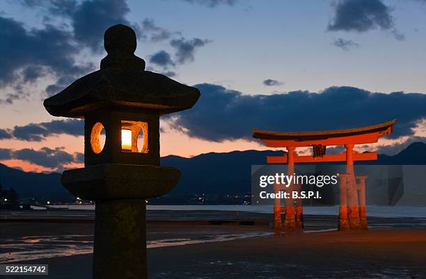 stone lantern and o-torii grand gate at itsukushima shrine on japan's sacred miyajima island - torii gate stock pictures, royalty-free photos & images