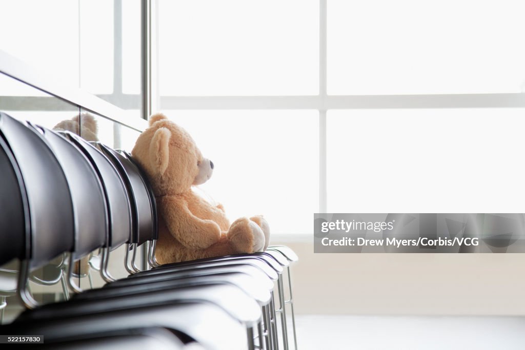 Teddy bear sitting on chair on hospital corridor