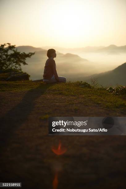 young japanese woman sitting on grass in the countryside - asago stock-fotos und bilder