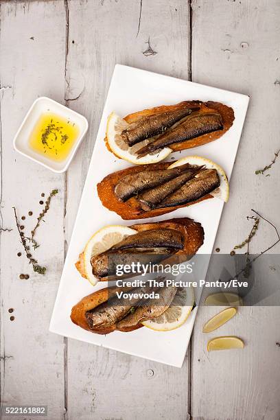 fish, spanish tapas - sprat with lemon on baked bread - sprat fish stock pictures, royalty-free photos & images