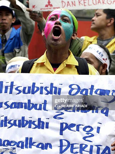 Worker of Japan's Mitshubishi company shouts slogans as he holds a banner reads: "We welcome Mitshubishi but while leaving just left suffering"...