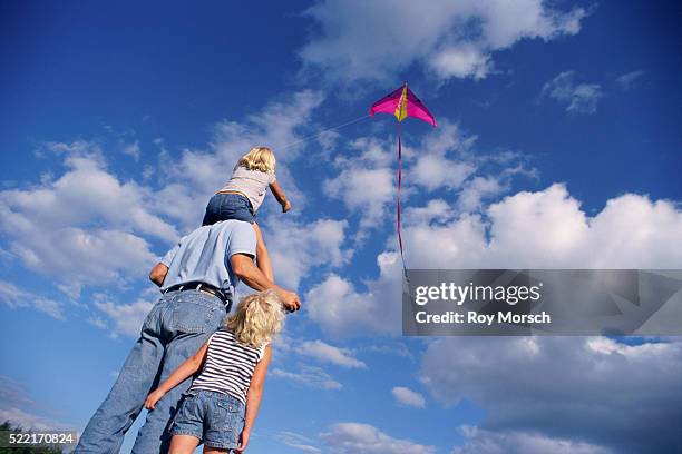 father and two daughters flying a kite - kite toy foto e immagini stock