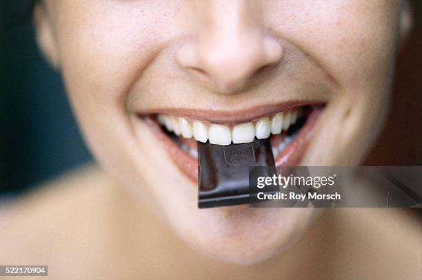 young woman eating chocolate - dark chocolate stock pictures, royalty-free photos & images