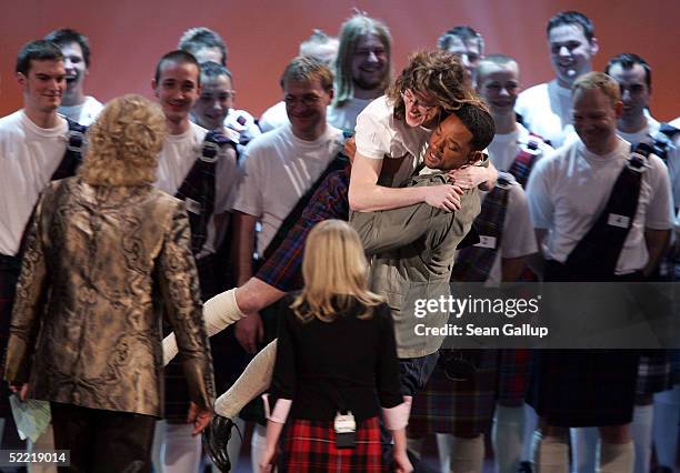 Actor Will Smith carries a man dressed in a Scottish kilt as host Thomas Gottschalk and contestant Julia Reichert look on during a bet on the "Wetten...