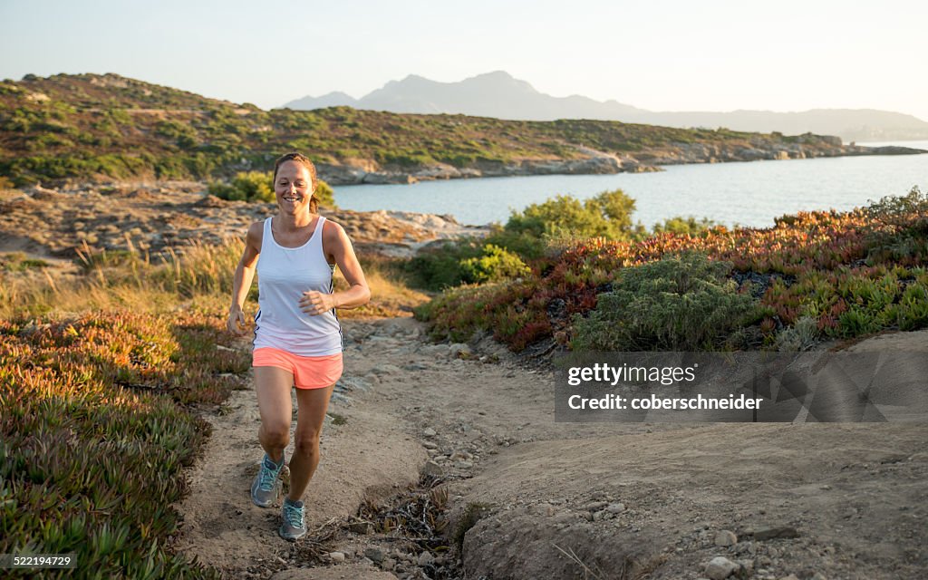 France, Corsica, woman trail running at coast