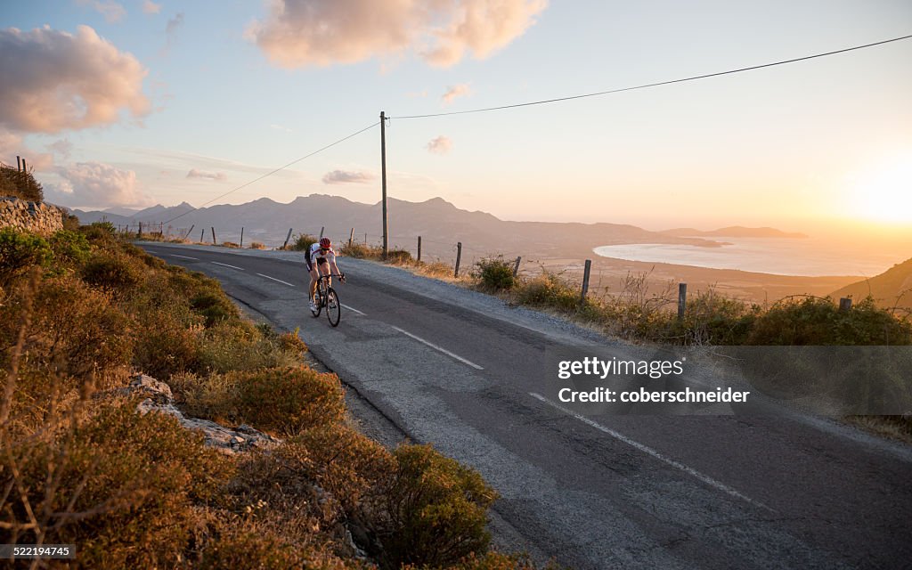 France, Corsica, Road cycling above sea at sunset