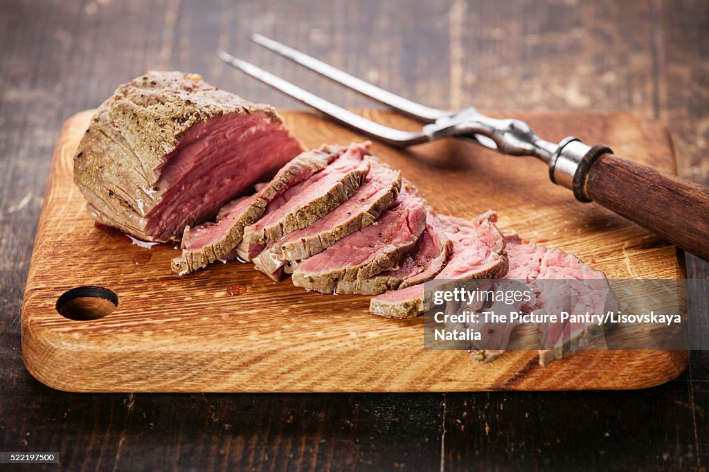 Roast beef on cutting board and meat fork