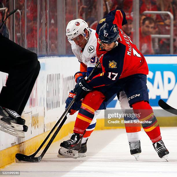 Derek MacKenzie of the Florida Panthers digs the puck out of the boards against John Tavares of the New York Islanders in Game One of the Eastern...