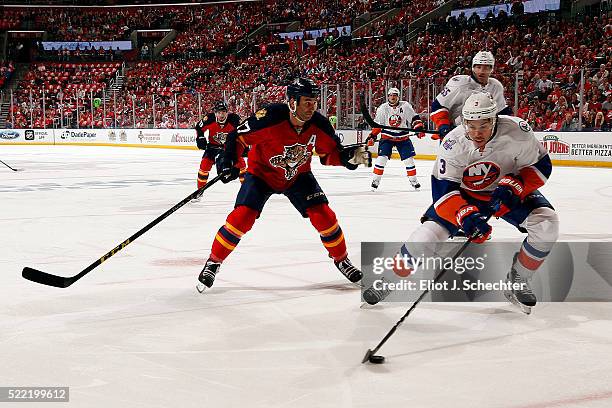 Travis Hamonic of the New York Islanders gathers the puck against Derek MacKenzie of the Florida Panthers in Game One of the Eastern Conference...