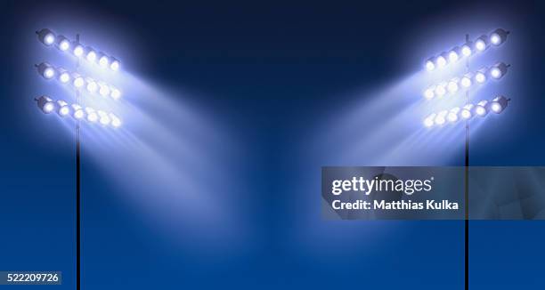 spotlights against blue sky - flutlicht stock-fotos und bilder