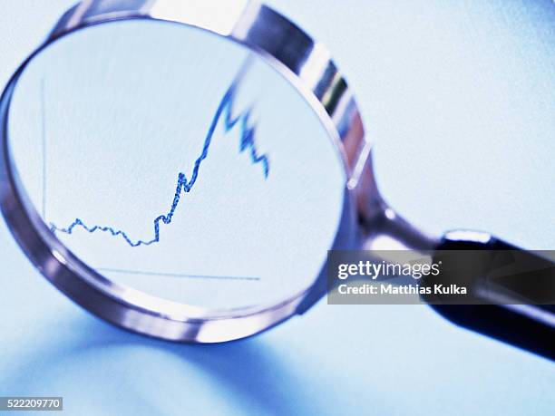 magnifying glass showing graph - kontrolle stock-fotos und bilder