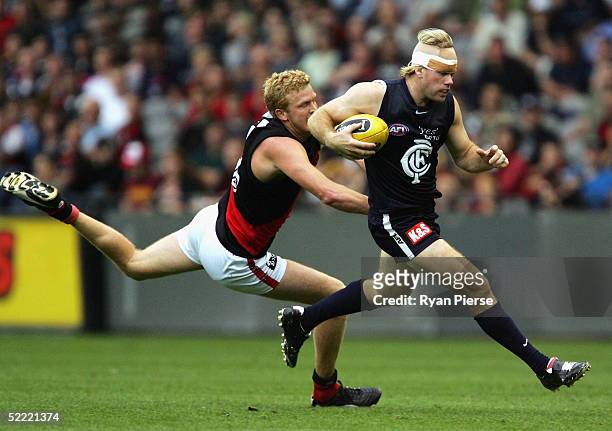 Nick Stevens for the Blues evades Dustin Fletcher for the Bombers during the round one AFL Wizard Cup match between the Carlton Blues and the...