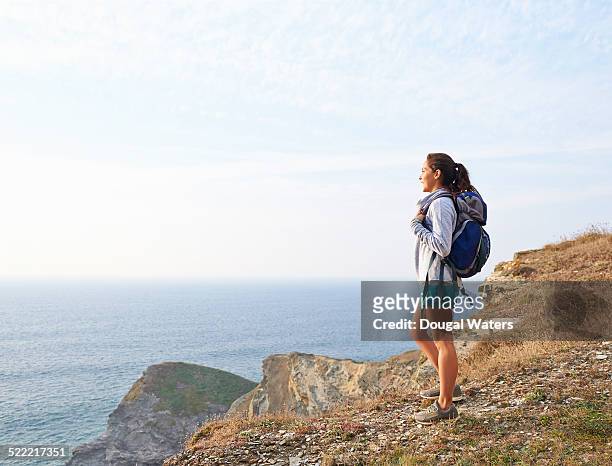 hiker looking out toward sea from cliff top. - hiking woman stock pictures, royalty-free photos & images