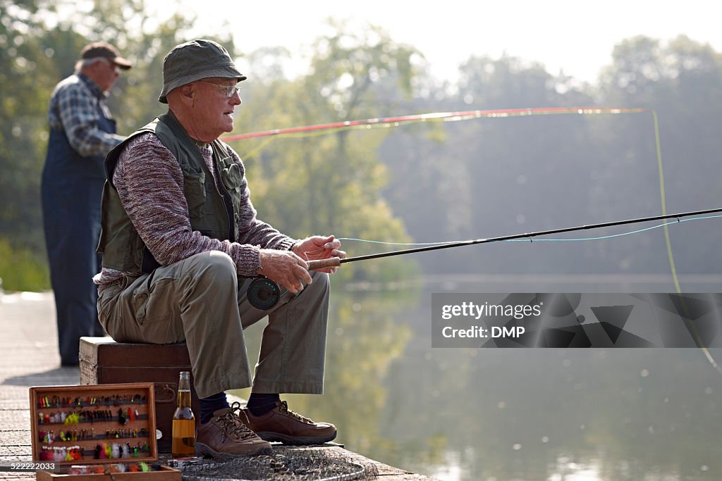 Relaxed fisherman fishing from the dock in river