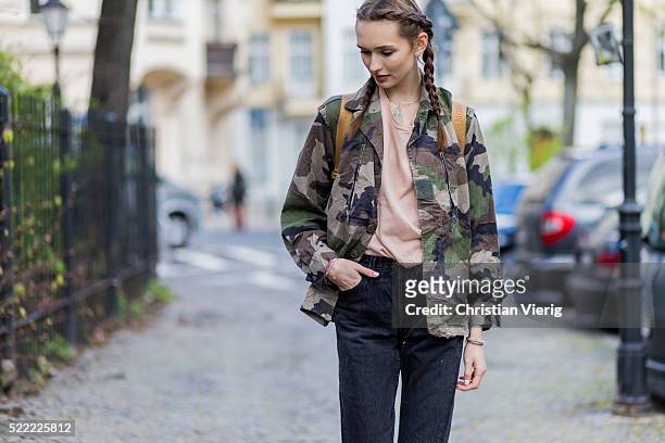 Fashion model Anna Wilken with braid hair wearing a camouflage jacket from Na-Kd, a MCM leather backpack, 501 black Levis denim jeans and a nude...