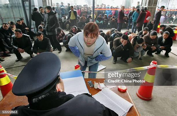 Policeman questions a suspect while in custody because of allegedly scalping train tickets at a railway station on February 20, 2005 in Chengdu of...