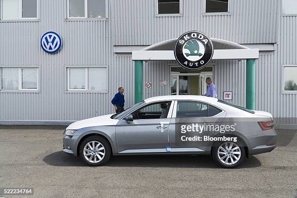Workers pass a Volkswagen AG logo near a new Skoda Superb automobile at the Eurocar PJSC automotive plant in Solomonovo, Ukraine, on Monday, April...