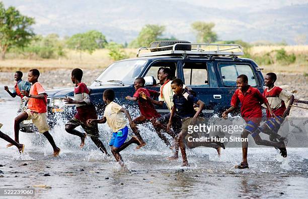 boys running alongside 4x4 vehicle in ethiopia - hugh sitton ethiopia stock pictures, royalty-free photos & images