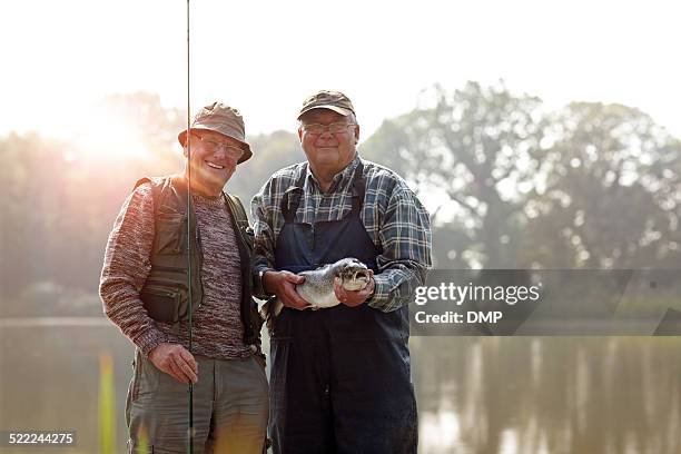 alter fischer mit angelrute und frischer fang - portrait fisherman stock-fotos und bilder