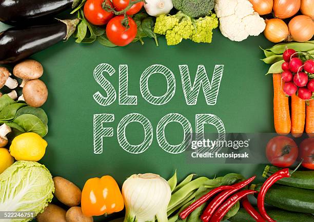 fresh organic vegetables on the "slow food" sign - langzaam stockfoto's en -beelden
