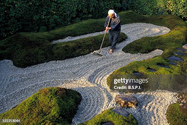 monk raking gravel in zen garden - 玉砂利 ストックフォトと画像