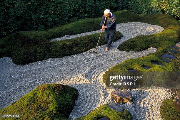 monk raking gravel in zen garden - japanese garden rake stock pictures, royalty-free photos & images