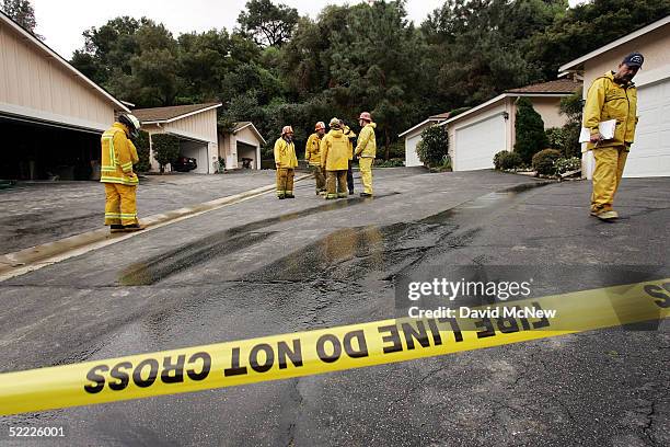 Firefighters stand outside a condominium after a 10-foot wall of mud smashed into it, filling the home to the ceiling and trapping three women inside...